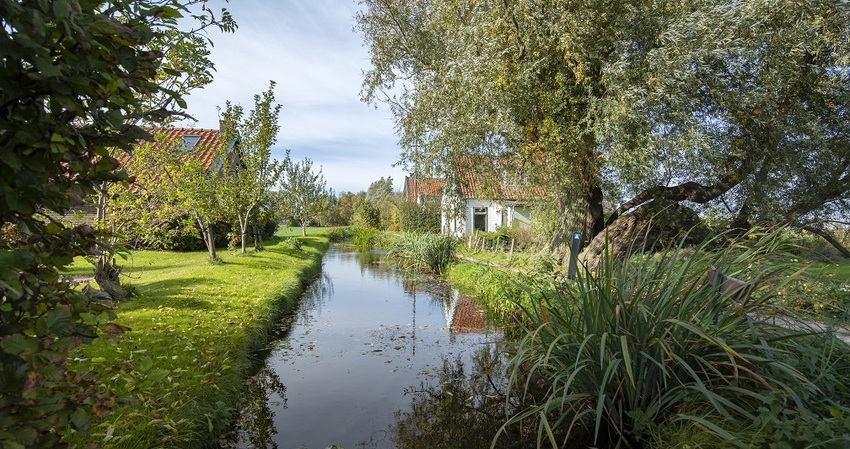 Foto van sloot met aan weerszijden huizen en bomen